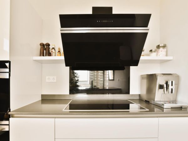 A modern kitchen with white cabinets and black stove hood over the range in this photo is taken from above it