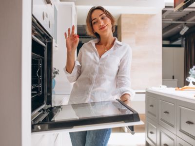 Woman baking at kitchen and looking into the oven