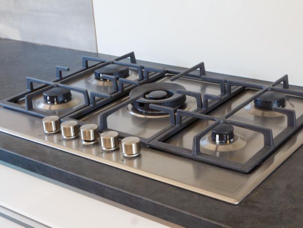 silver gas hob with black grate on top and it has 5 knobs
